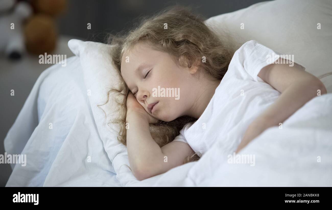 Petite fille blonde de dormir dans un lit confortable à la maison, reste calme pour une bonne santé Banque D'Images