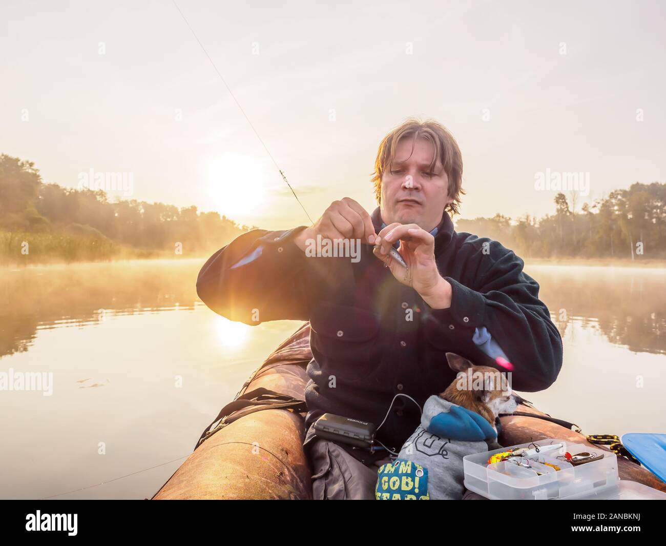 Les prises des pêcheurs de poissons sur un bateau belle petite rivière tôt le matin au lever du soleil avec son chien. Banque D'Images
