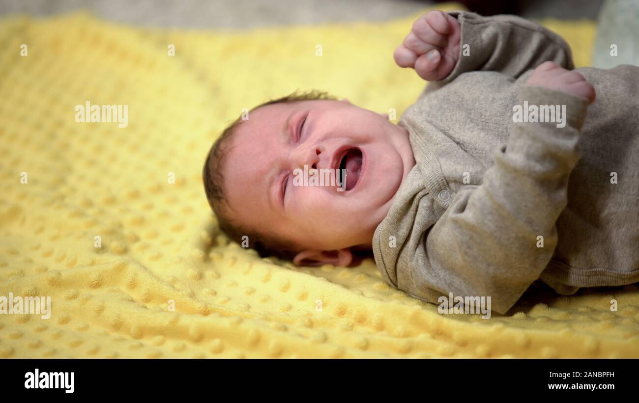 Bébé nouveau-né allongé et pleurer souffrant de coliques abdominales, l'émergence de la dent Banque D'Images