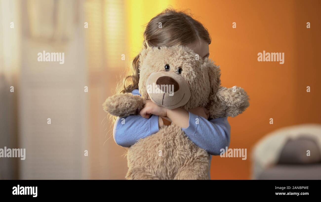 Jeune fille timide, d'âge préscolaire se cacher derrière ours, puérils problèmes psychologiques Banque D'Images
