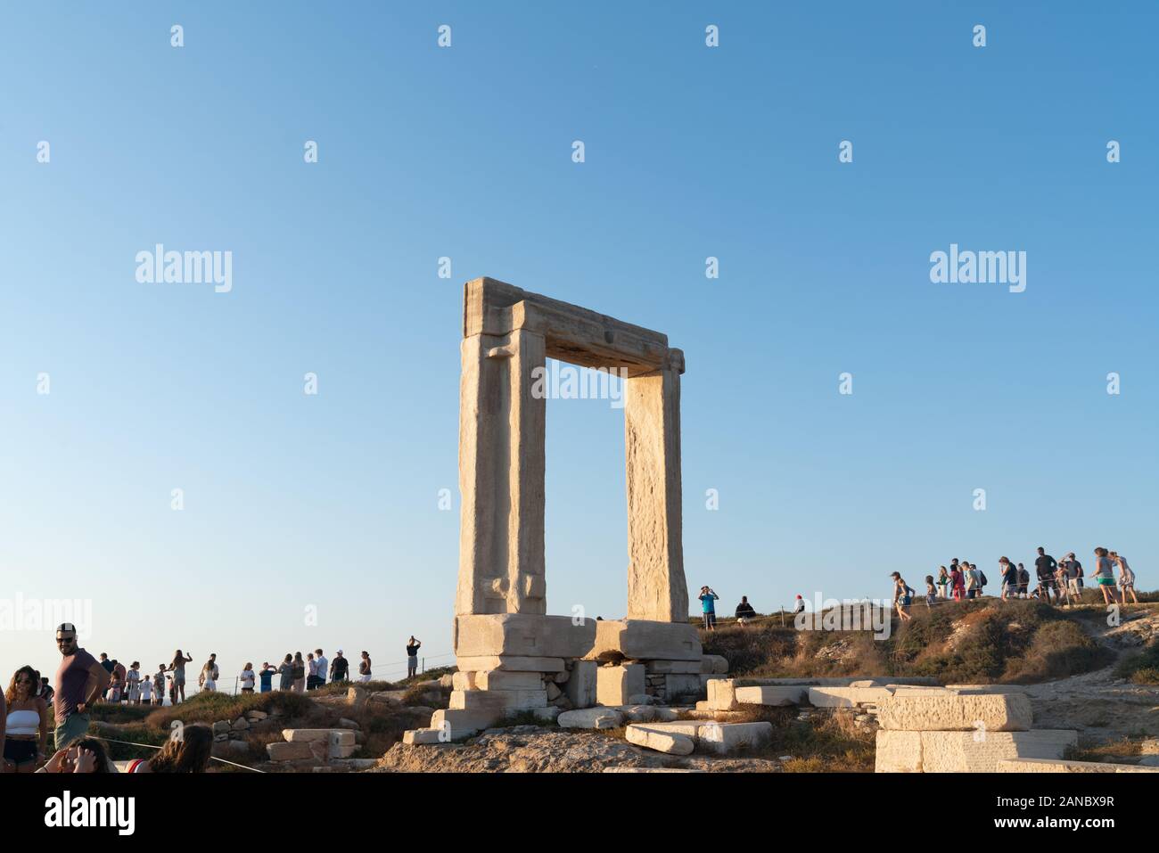 Naxos Grèce - le 12 août 2019 ; porte entre les vestiges du temple d'Apollon sur l'îlot de Palatia auprès des touristes qui sont venus pour voir le coucher du soleil de cette fa Banque D'Images