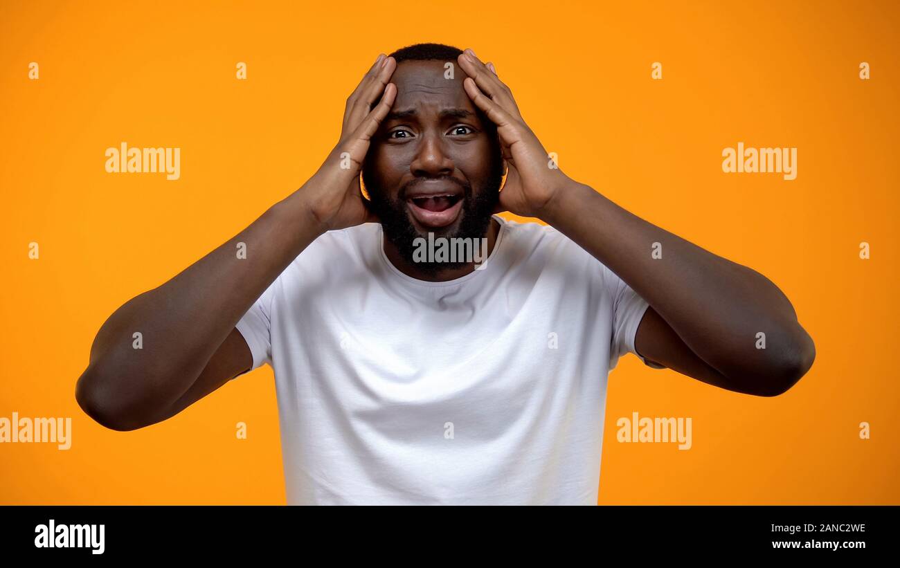 L'homme afro-américain choqué holding head, problèmes de la vie, de mauvaises nouvelles, les commères Banque D'Images