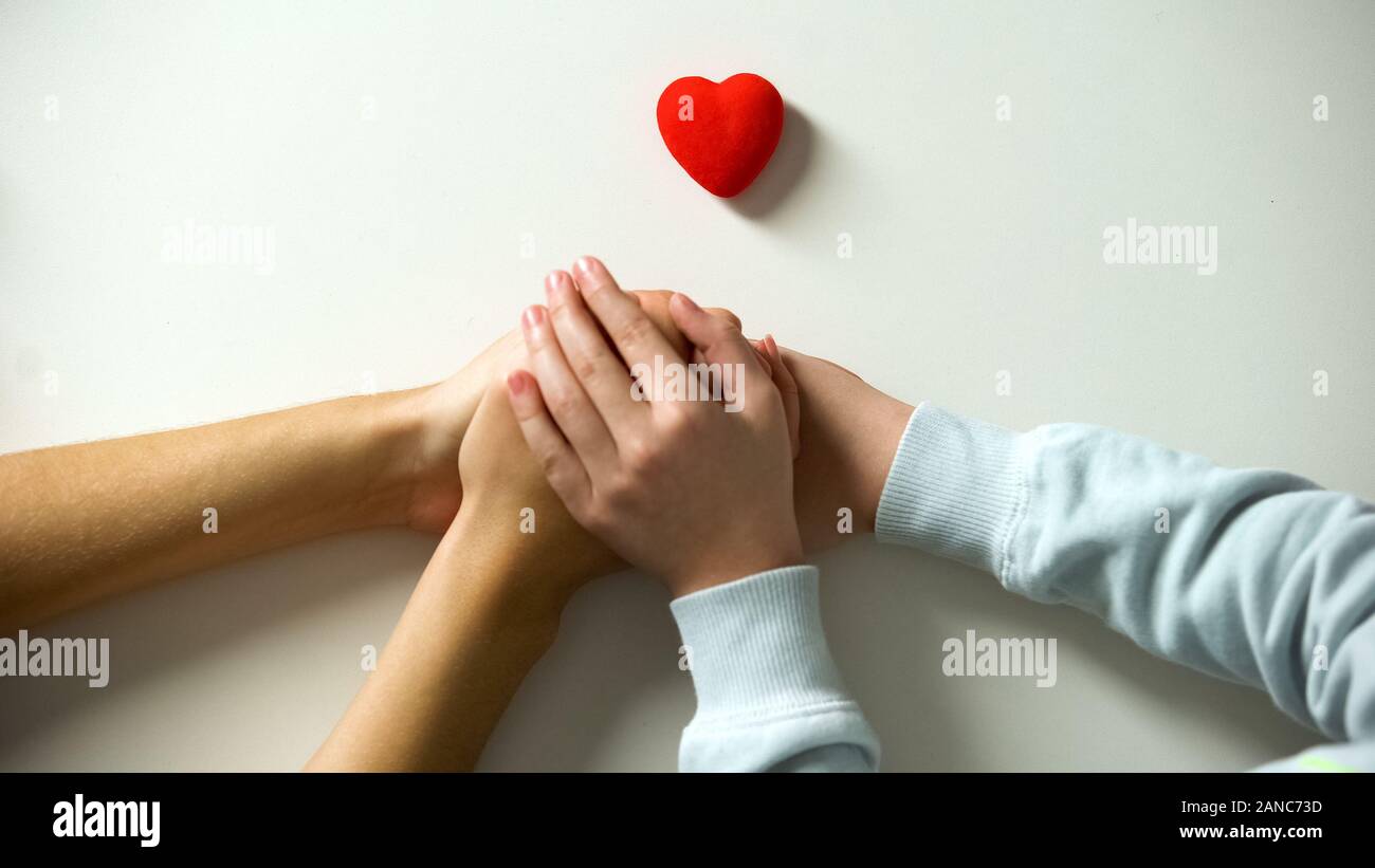 Enfant et adulte personne tenant les mains, coeur signe sur fond blanc, la garde Banque D'Images