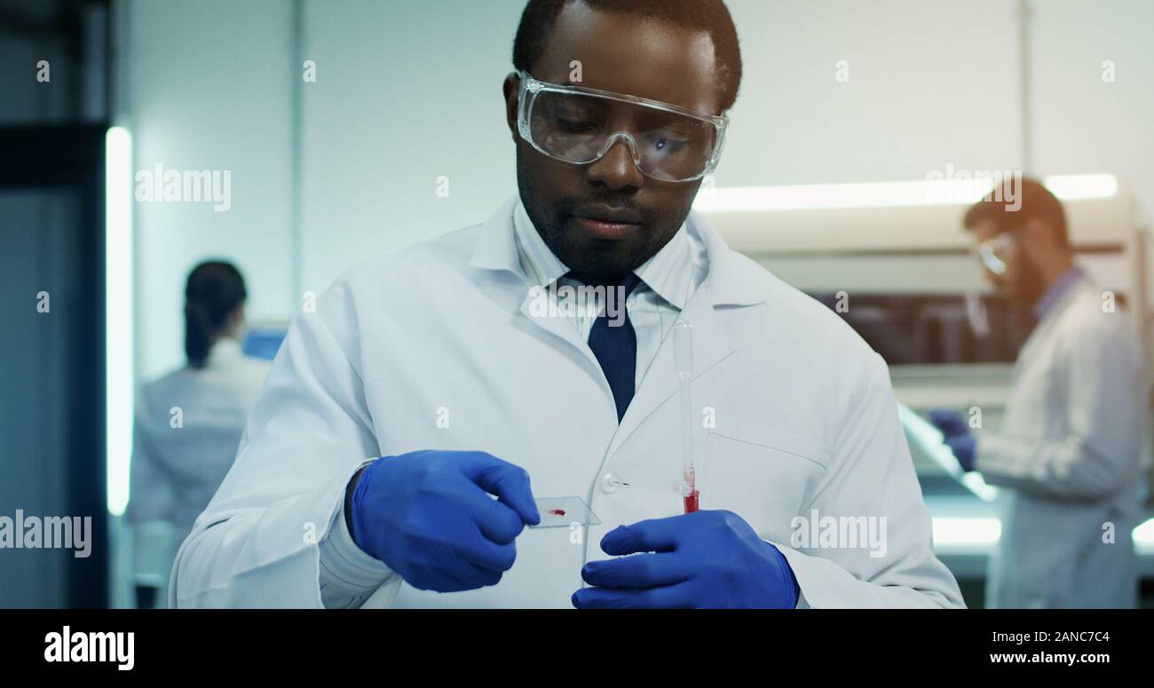 Jeune homme afro-américain de chercheur en laboratoire un test sanguin avec un tube dans les mains. Portrait. Banque D'Images
