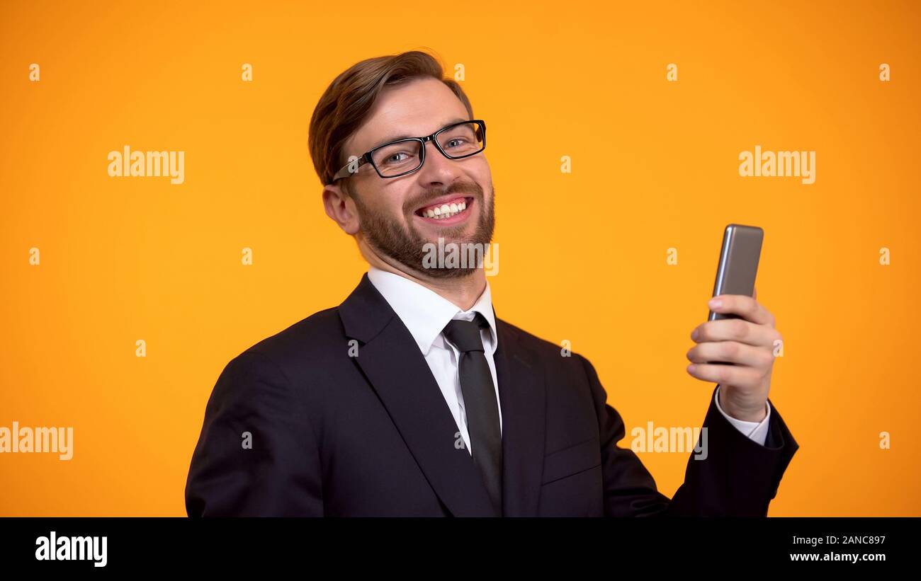 Homme heureux sourire sincèrement holding smartphone en main, le crédit favorable, l'app Banque D'Images