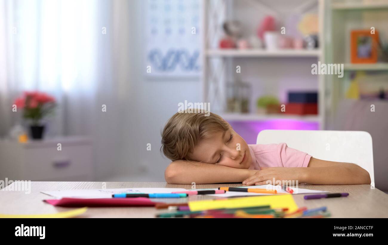 Homme bambin dormir sur bureau, crayons de couleur et sur la table de jardin Banque D'Images