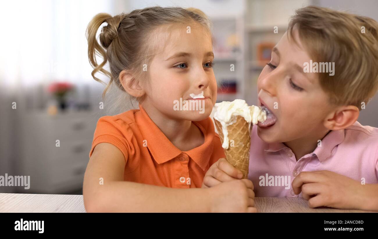 Adorable boy and girl eating ice-cream ensemble, assis à la table d'accueil, de l'alimentation Banque D'Images