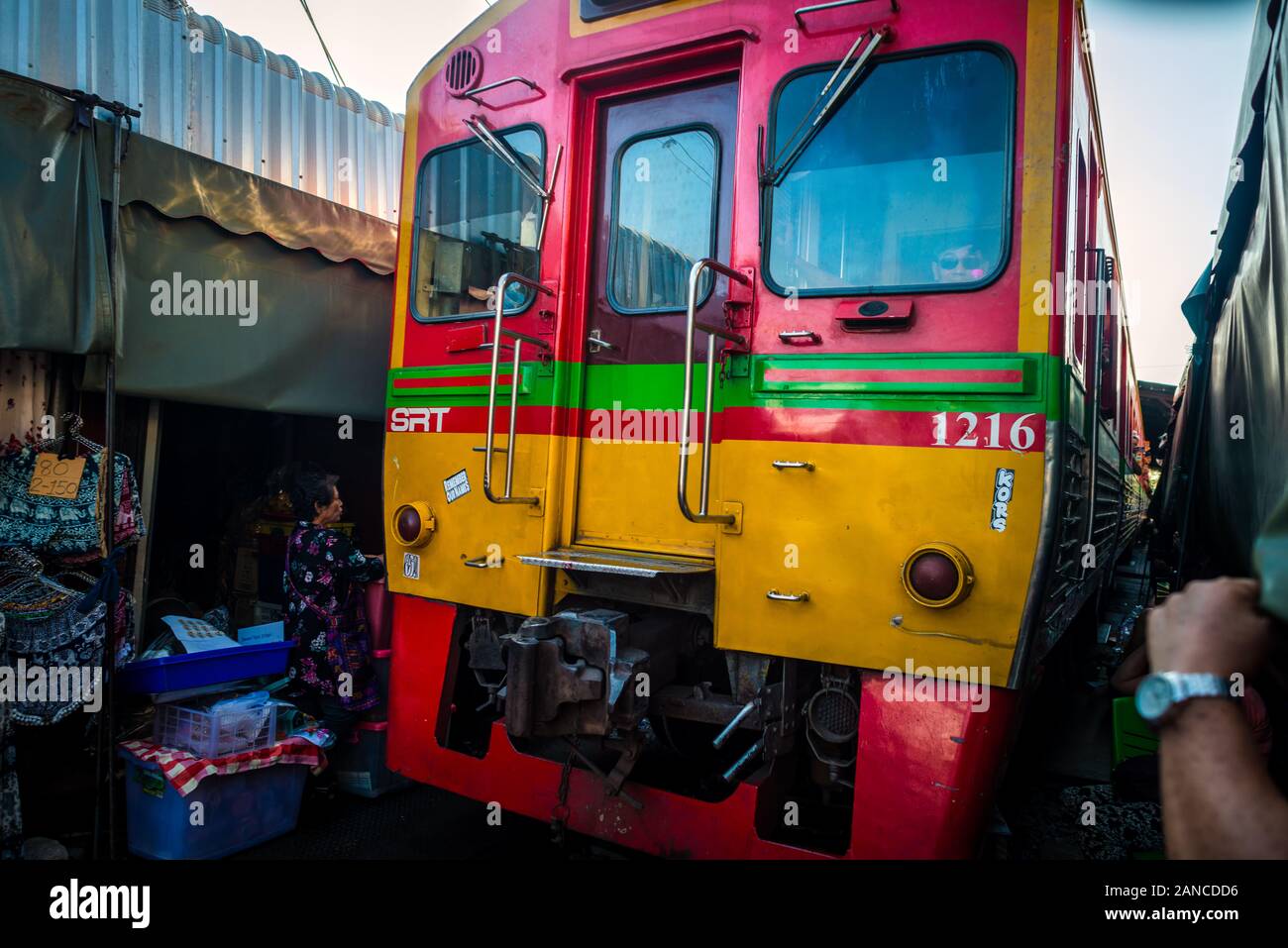 Mae Klong/Thailand-08December2019: Gare de Mae Klong avec voies et train passant par le marché quotidien avec des vendeurs vendant tout. Banque D'Images