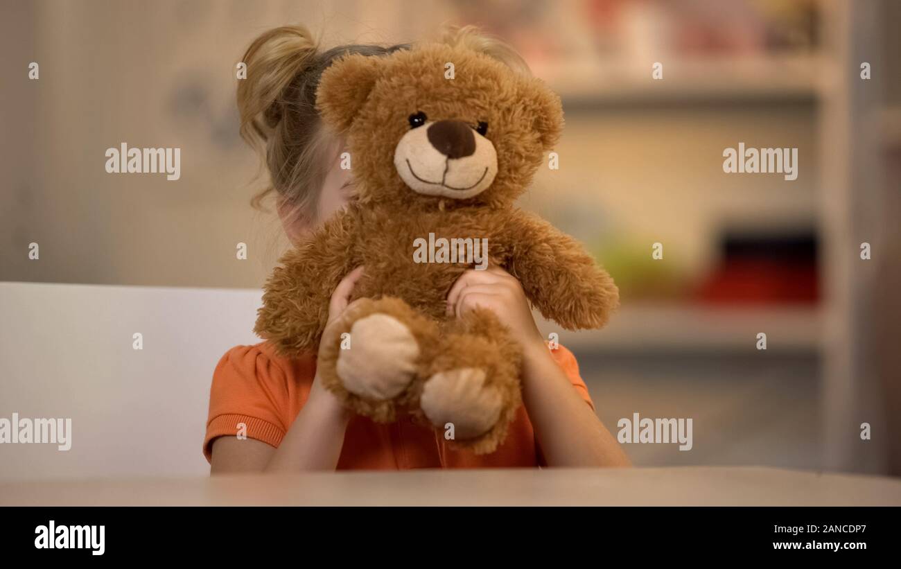 Smiling girl holding adorable ours en peluche brun, joyeux enfant, enfance heureuse Banque D'Images