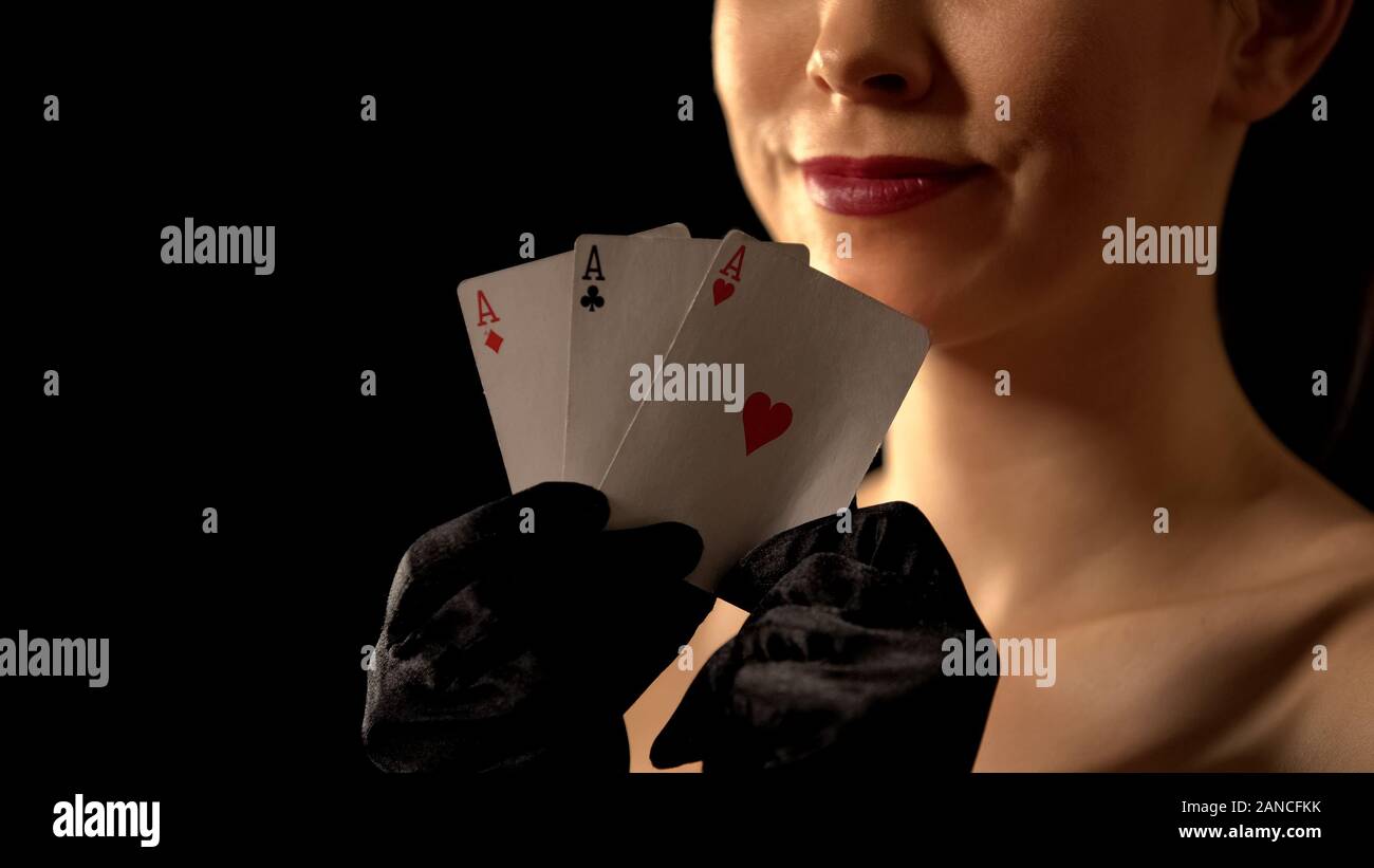 Dame souriant montrant trois des as en appareil photo, combinaison de poker gagnant, Banque D'Images