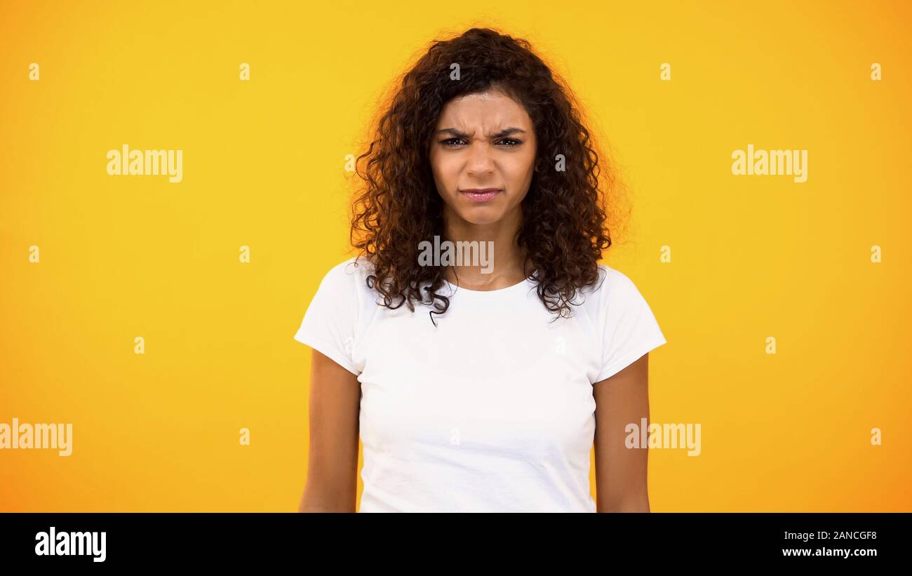 Femme en colère à la millénaire appareil photo sur fond orange, la dépression, les soucis Banque D'Images