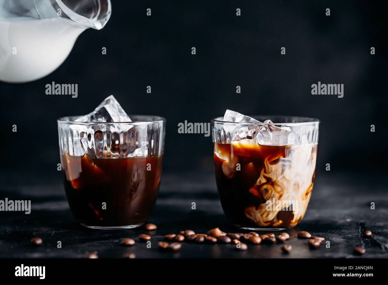 Verser le lait dans un verre de café expresso avec de la glace Banque D'Images