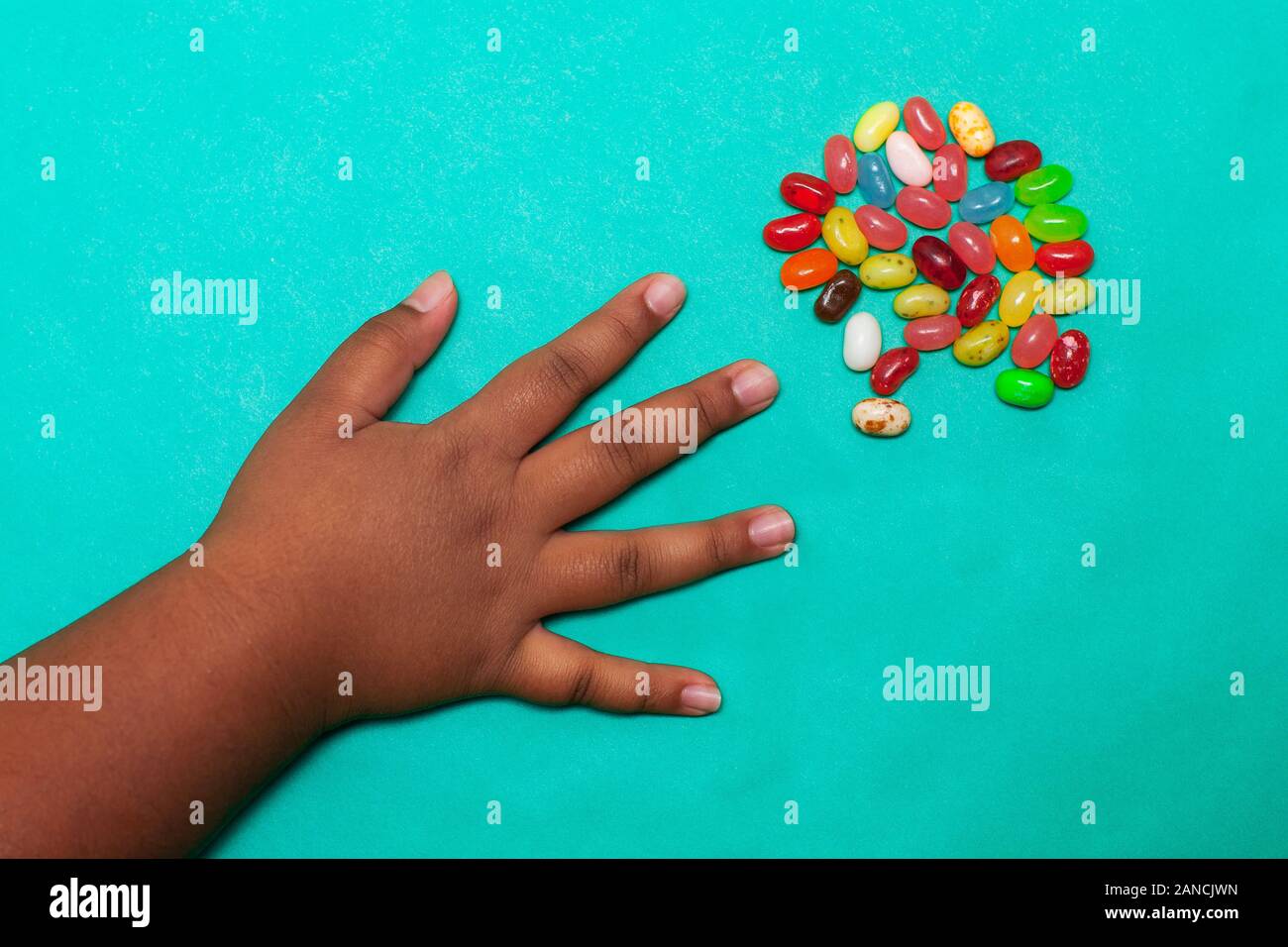 Une petite main sur les enfants latino pour attraper les bonbons d'une petite portion d'une variété de saveurs sur une table de couleur vive. Banque D'Images