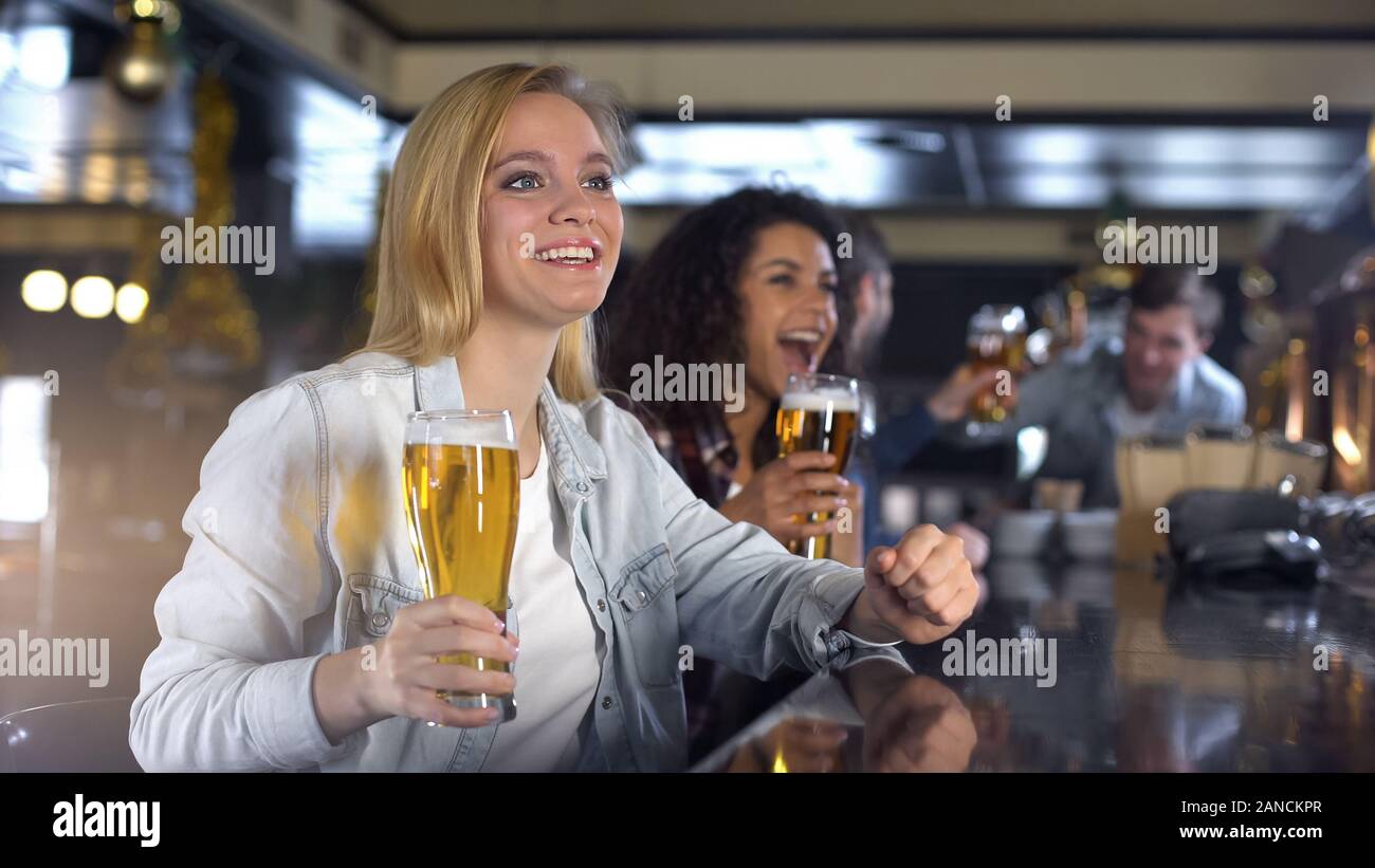 Dame blonde pour encourager l'équipe nationale, ce verre de bière pour la victoire dans le jeu Banque D'Images