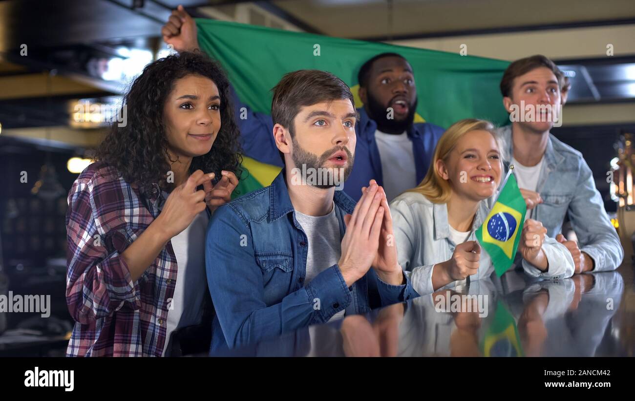 Impatients fans de football avec l'équipe nationale brésilienne des drapeaux dans le jeu Banque D'Images