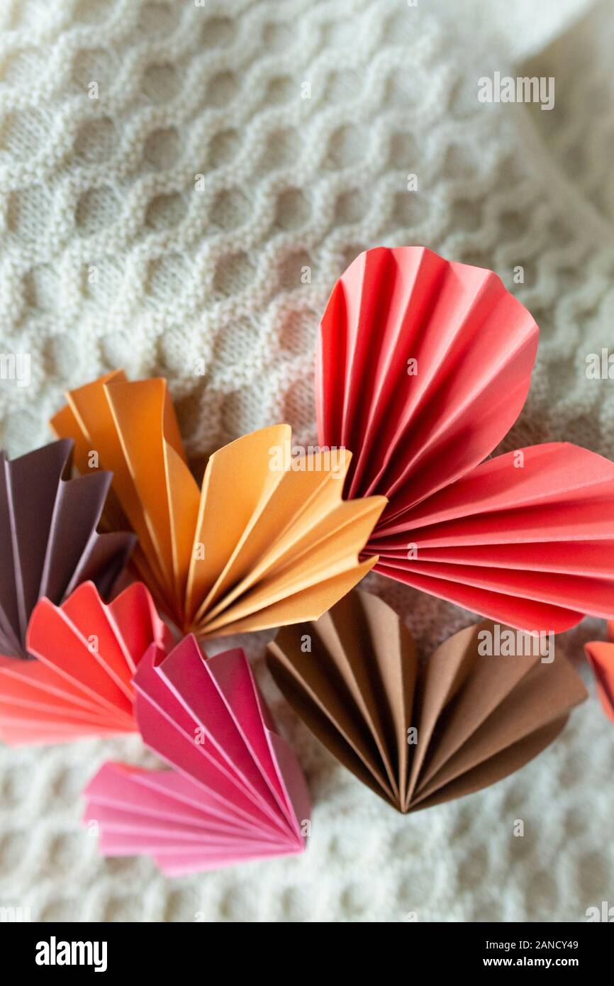 Coeurs en papier pliés disposés sur un fond en tissu neutre Banque D'Images
