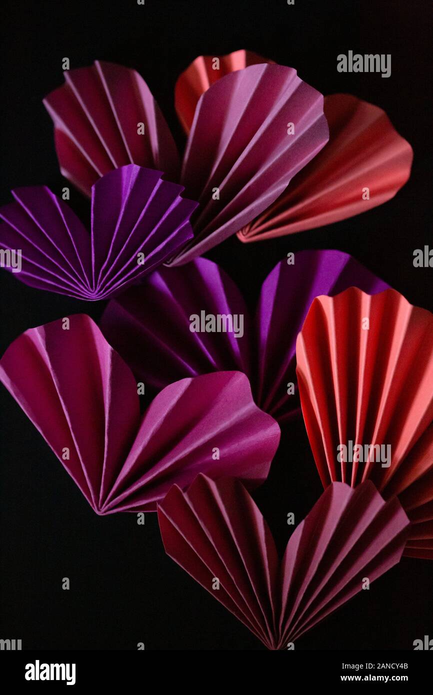 Coeurs de papier pliés roses et violets sur fond noir Banque D'Images