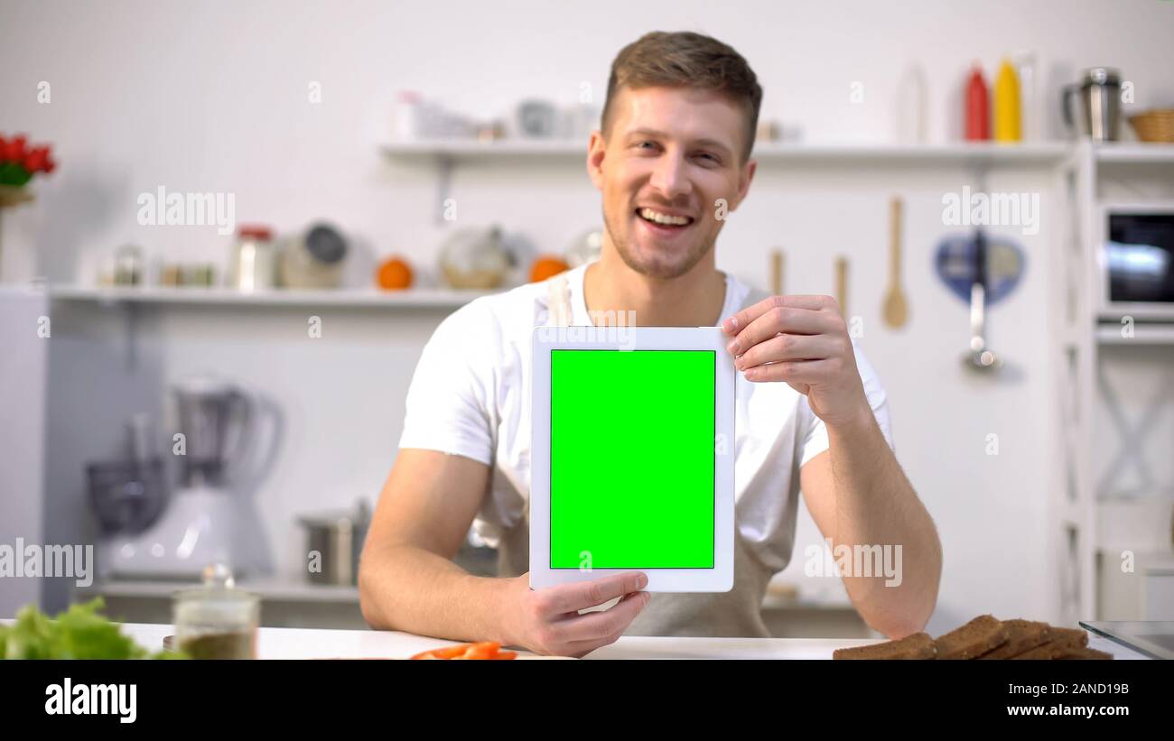Handsome man holding tablet avec l'écran vert, application des cours de cuisine Banque D'Images