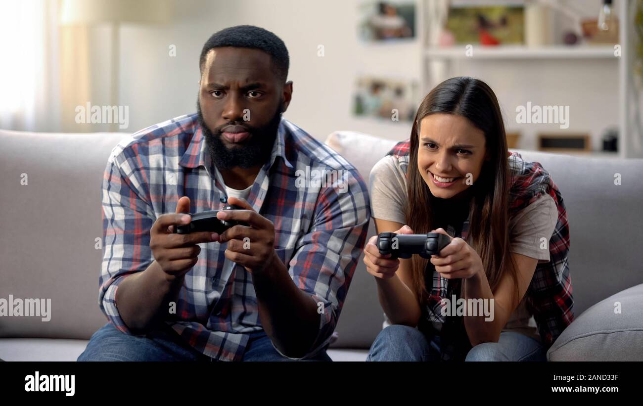 Joli couple multiethnique s'amusant, jouer au jeu vidéo à la maison, les loisirs Banque D'Images