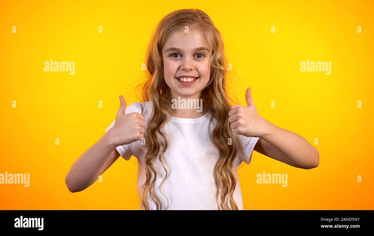 Fille de l'adolescence émotionnelle faisant double thumbs-up, extrêmement satisfait, enfant promo Banque D'Images