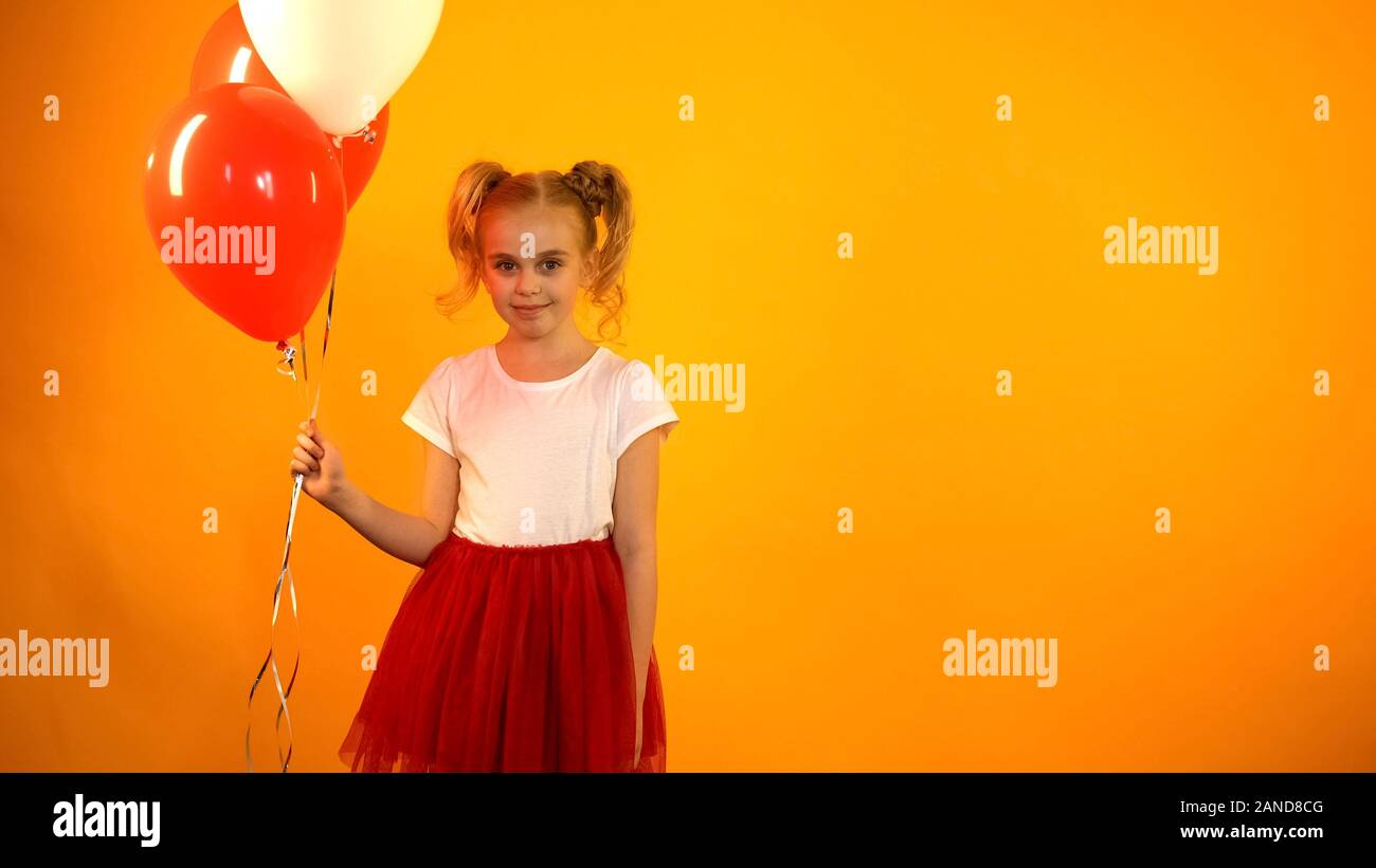 Jolie fille avec des ballons d'air à la recherche d'appareil photo, la célébration d'anniversaire Banque D'Images