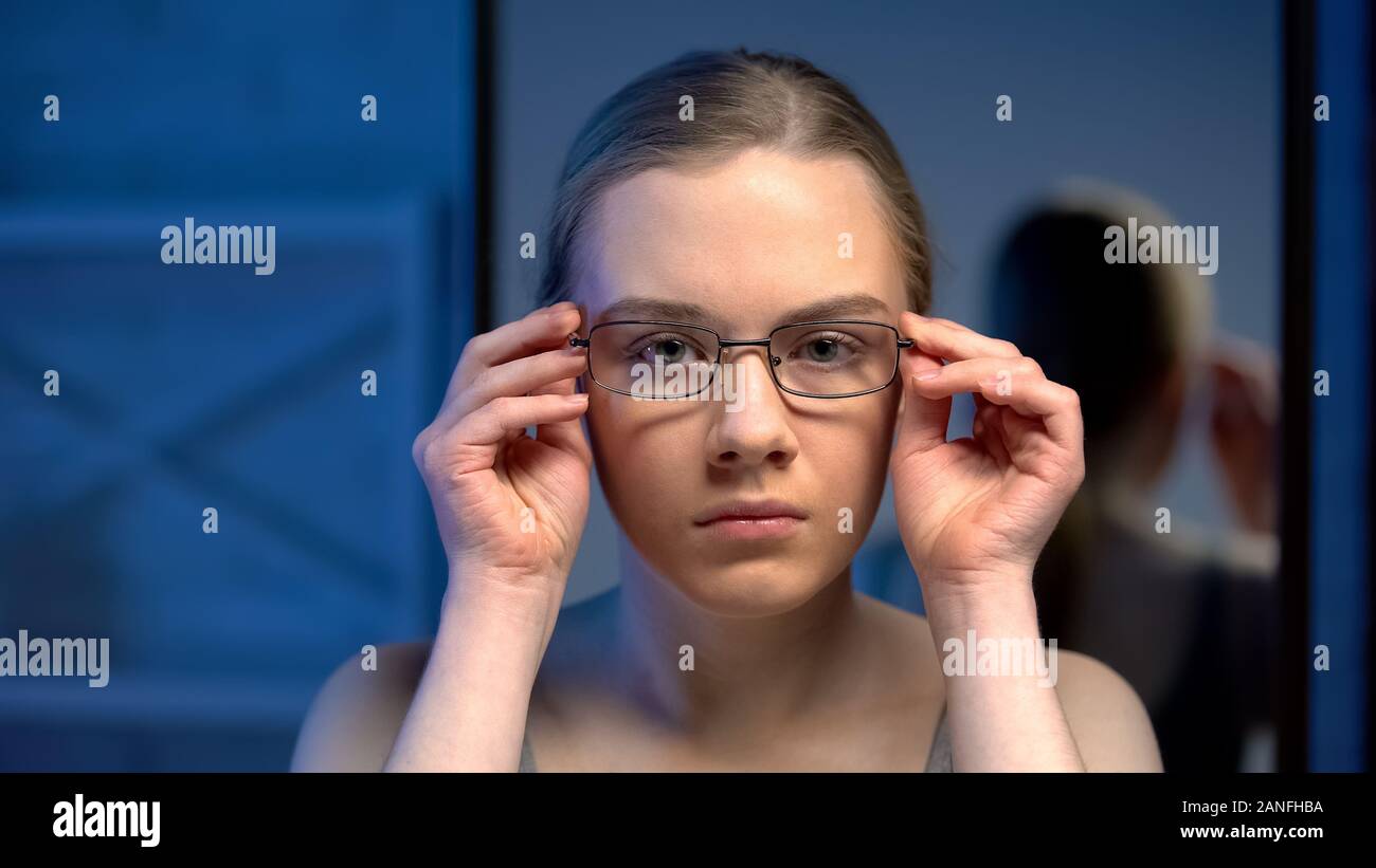 Jeune femme malheureuse de mettre les lunettes, insatisfaite de la  réflexion de miroir Photo Stock - Alamy