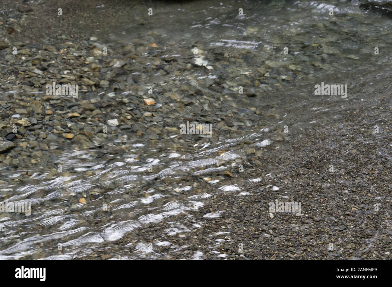 Pierres gris forme le lit d'une rivière peu profonde Banque D'Images