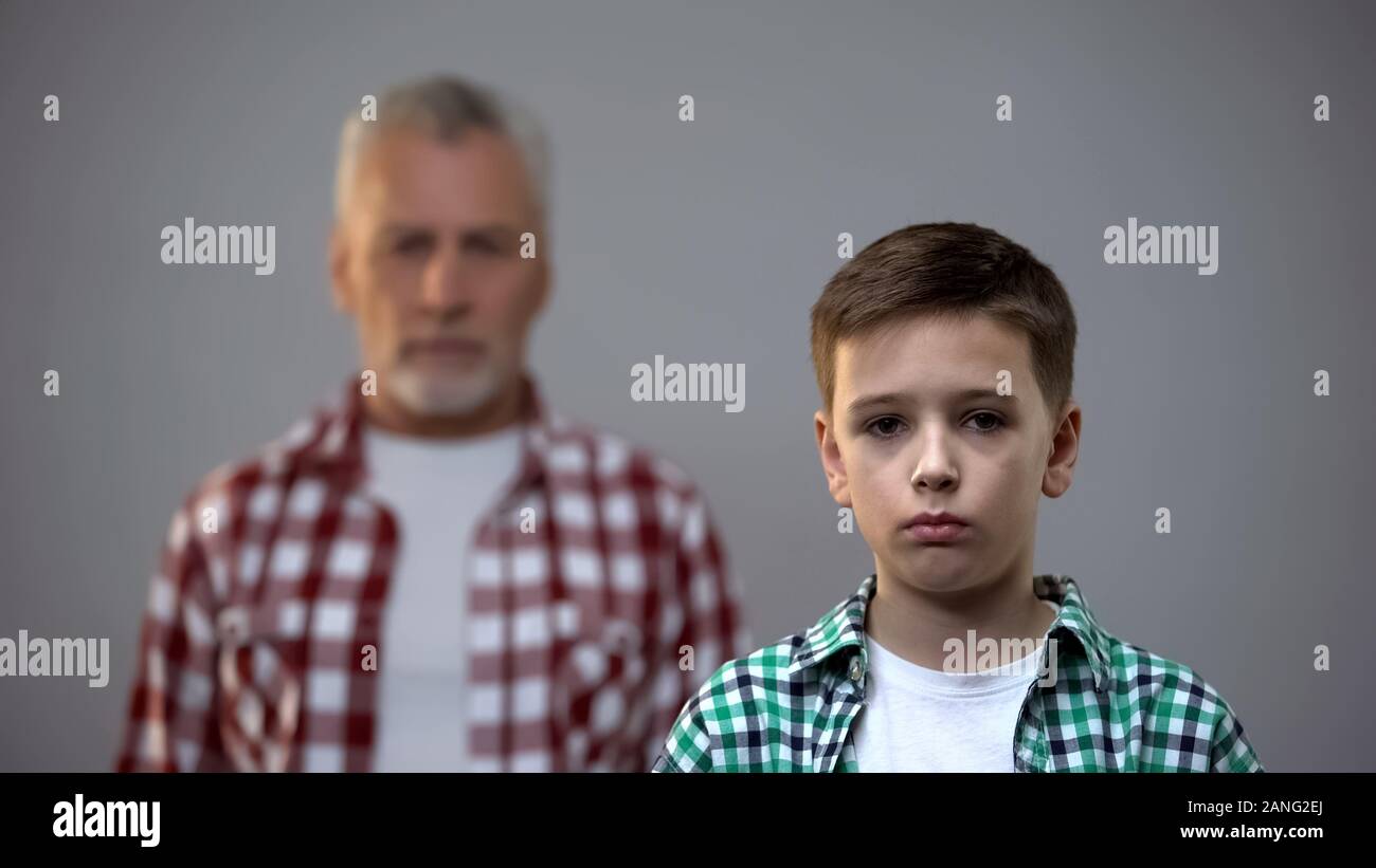 De graves teen boy looking at camera, à l'âge de femme derrière, raccordement avec les ancêtres Banque D'Images