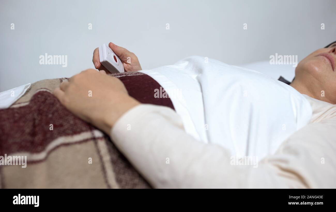 Femme malade in hospital bed holding bouton d'urgence, médecine et soins de santé Banque D'Images