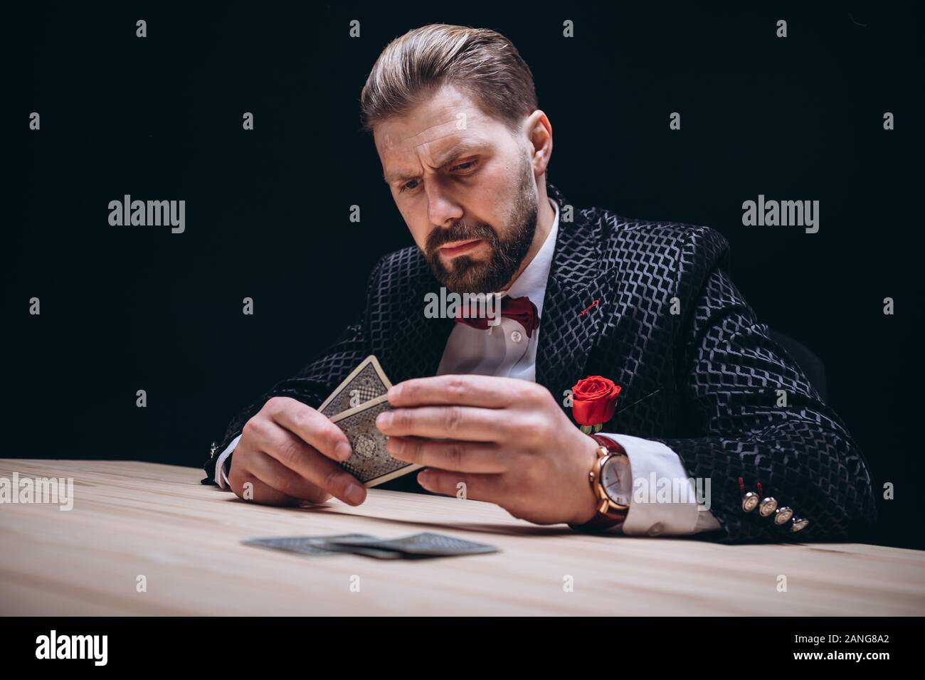 Homme barbu avec Bow Tie Contrôle de la main de Poker Banque D'Images