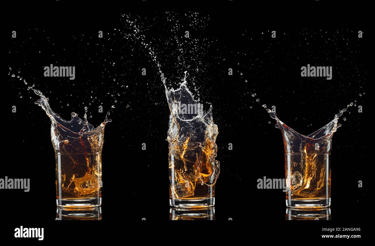 Verre de whisky avec splash isolé sur fond noir Banque D'Images