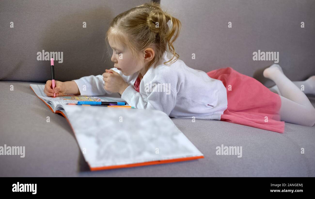 Cute little girl dessiner avec des marqueurs dans un livre à colorier, la thérapie par l'art et passe-temps Banque D'Images