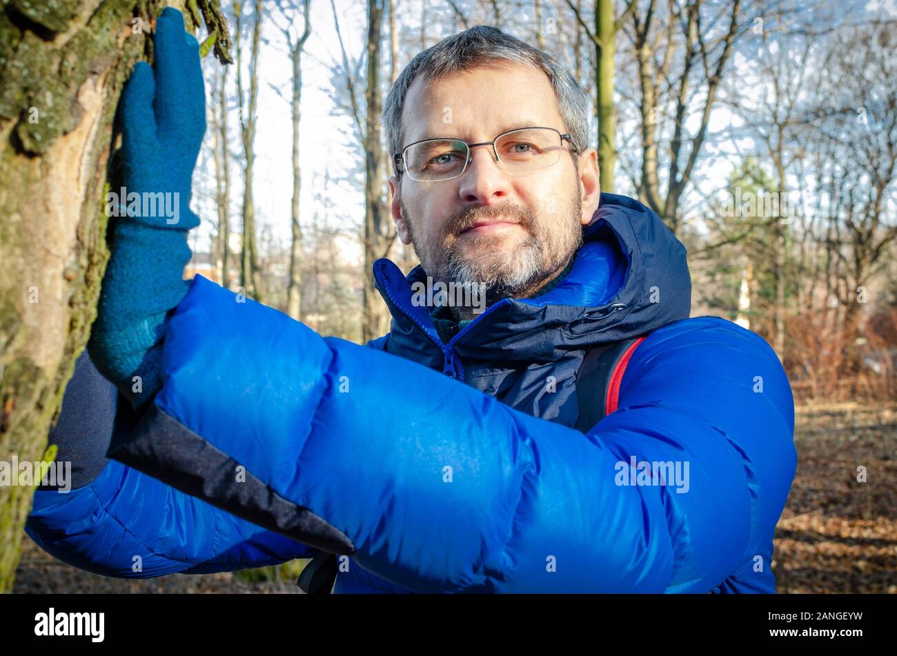 Homme d'âge moyen dans la région de blue Down Jacket repos dans la forêt. Banque D'Images