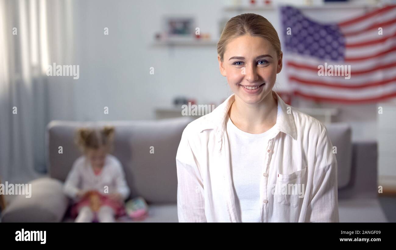 Patriot joyeuse woman looking at camera, fille jouant sur canapé contre US flag Banque D'Images