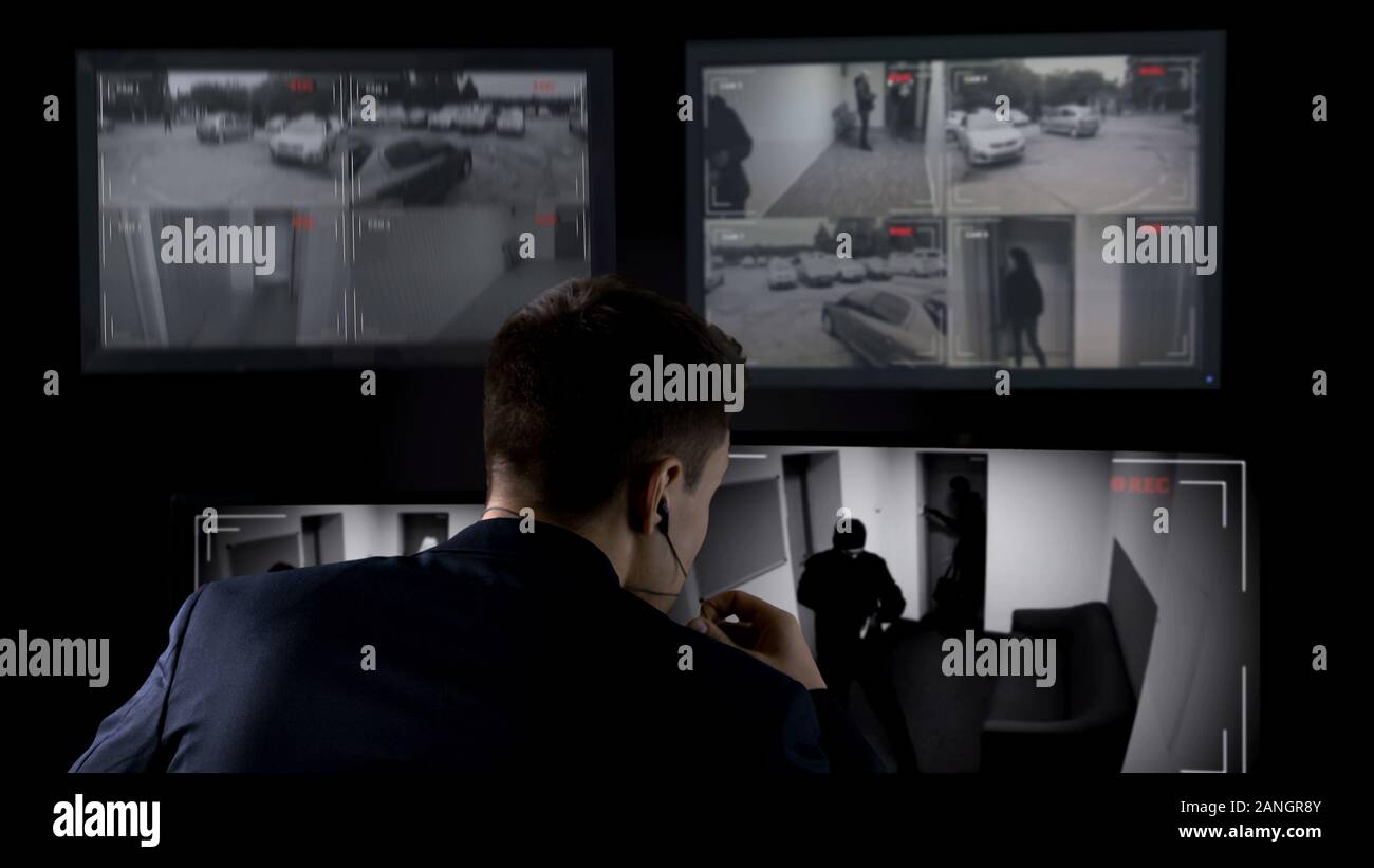 Gardien de sécurité en regardant des images de vidéosurveillance, appelant la police, voleur rupture dans la construction Banque D'Images