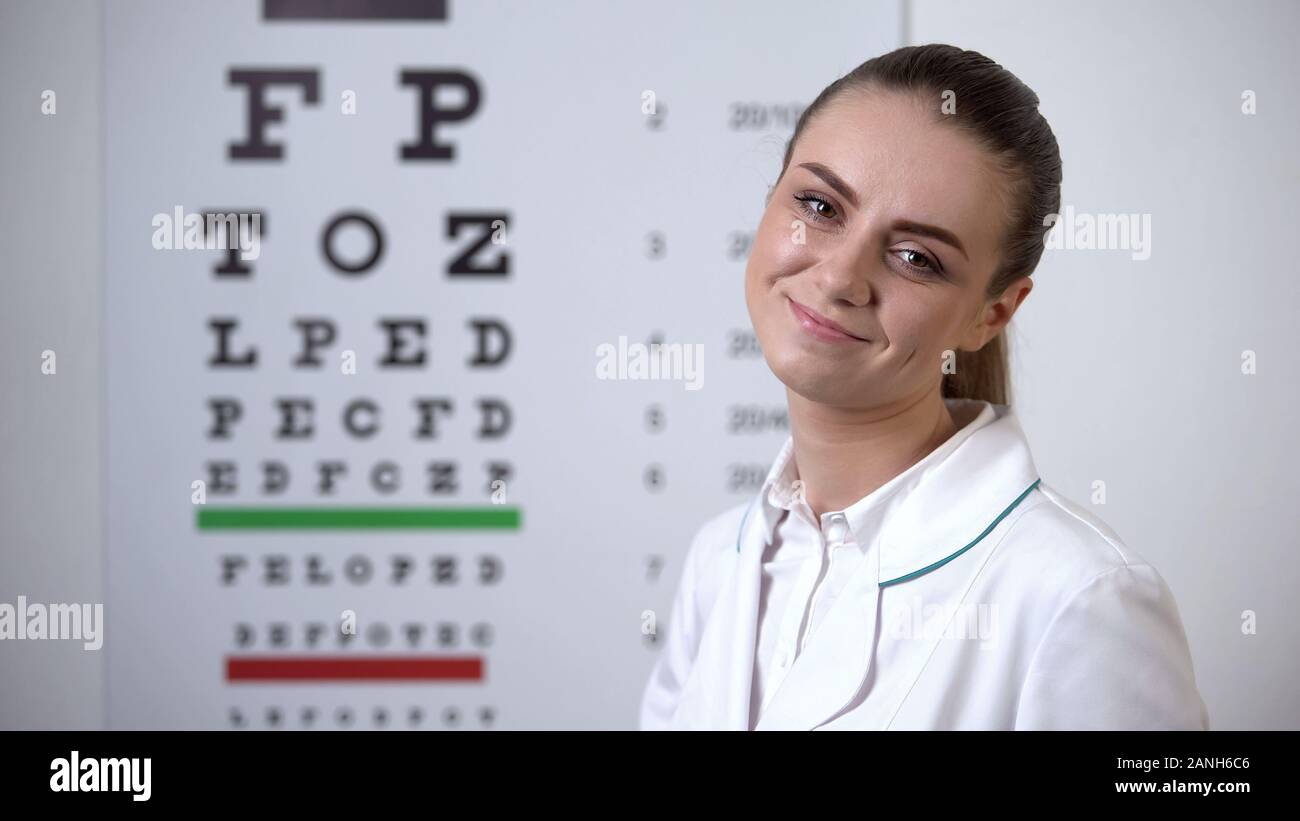 Smiling ophtalmologiste posant près de l'œil en vision professionnelle clinic Banque D'Images