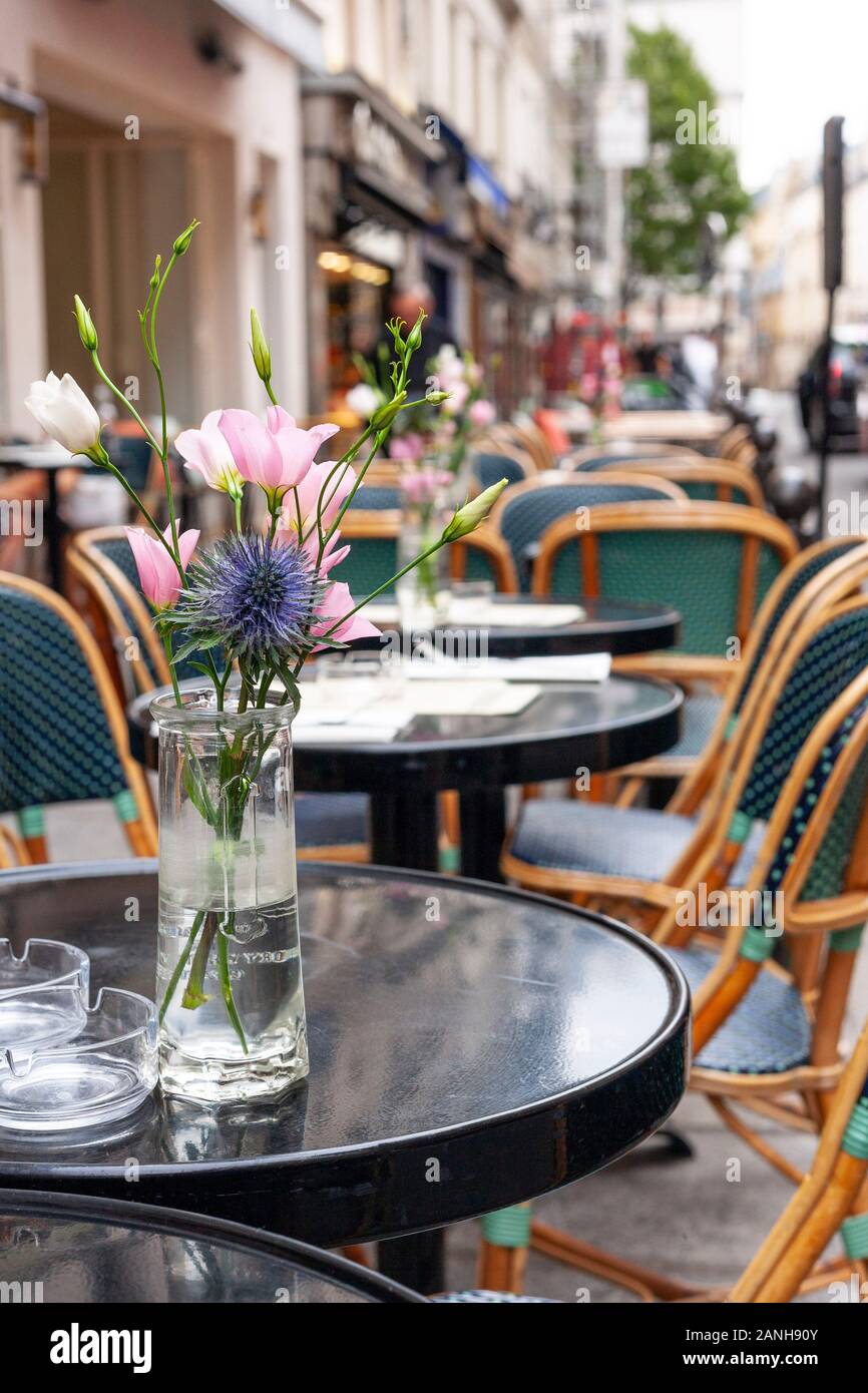 Fleurs sur les tables d'un café parisien à Paris, France sur la rue de Buci. Banque D'Images