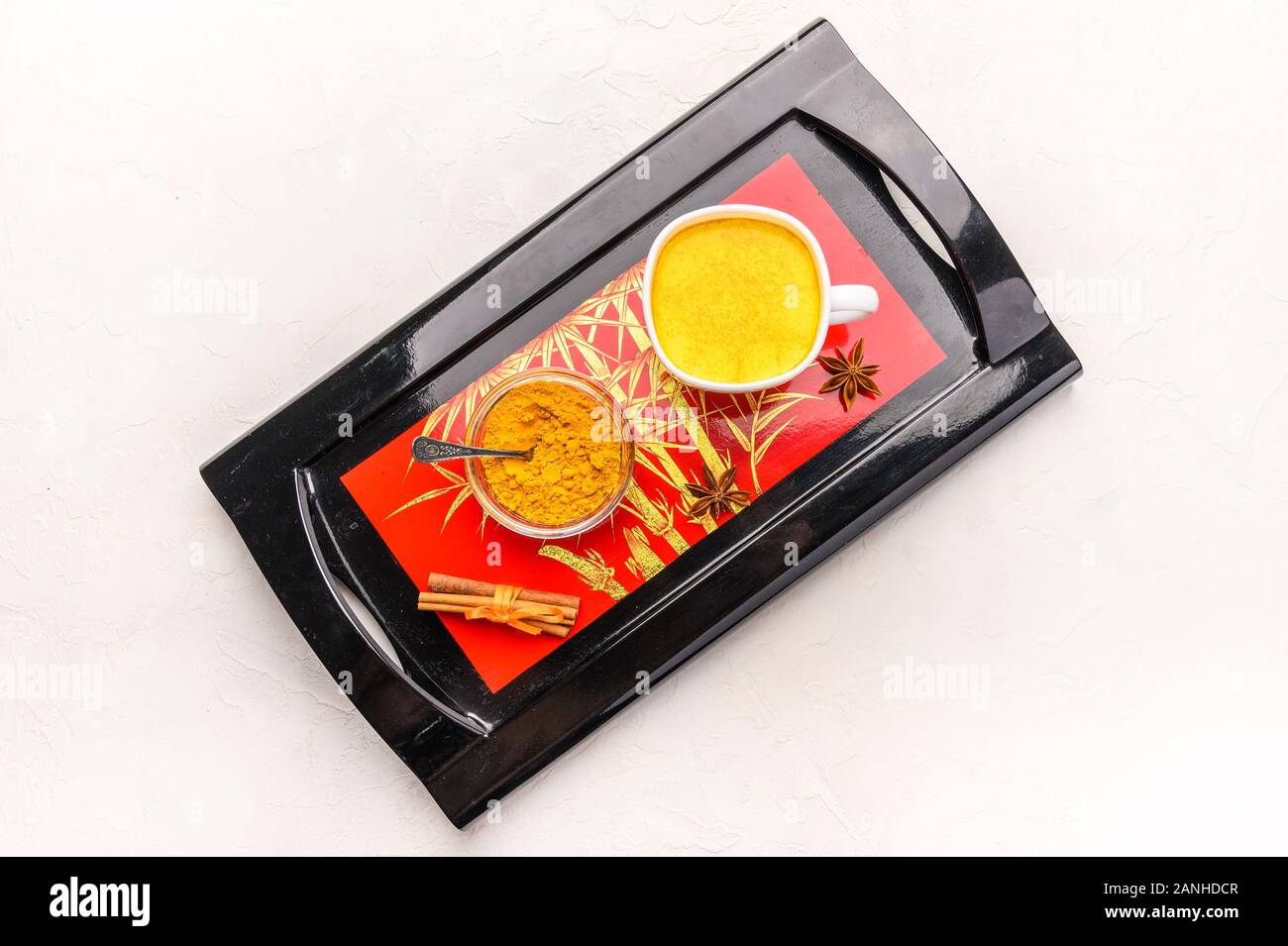 Masala chai thé indien traditionnel avec des épices, de la cannelle, d'anis et de cardamome dans une tasse blanche sur un plateau noir Banque D'Images