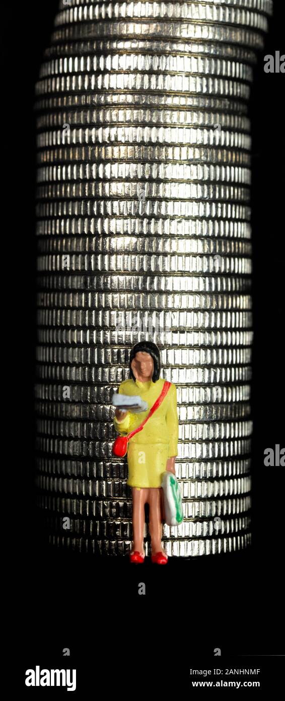 Figurine miniature femelle, debout devant une pile de pièces Banque D'Images