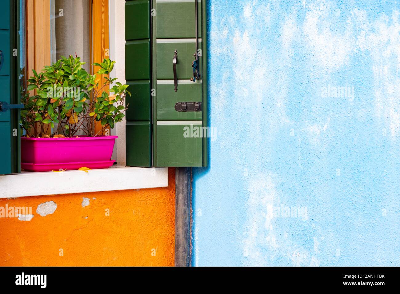 Façade de maison coloré en pointillés bleus italie pot de fleur rose mur murs orange, des volets verts, l'obturateur en bois design italien, joli concept burano Banque D'Images