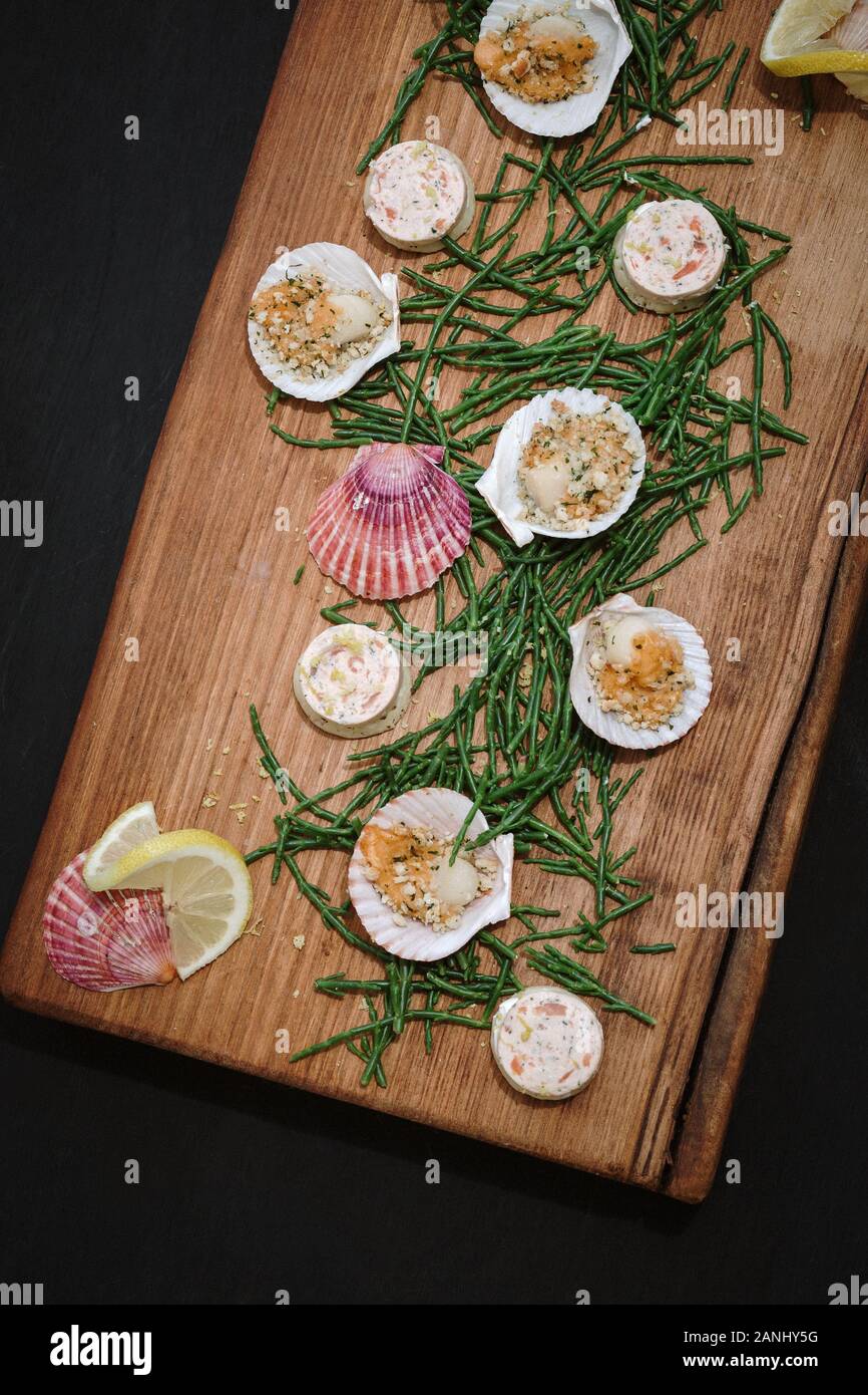 Plateau de fruits de mer : canapés servis sur une planche en bois avec des pétoncles et des quartiers de saphir et de citron. Vue de dessus. Banque D'Images