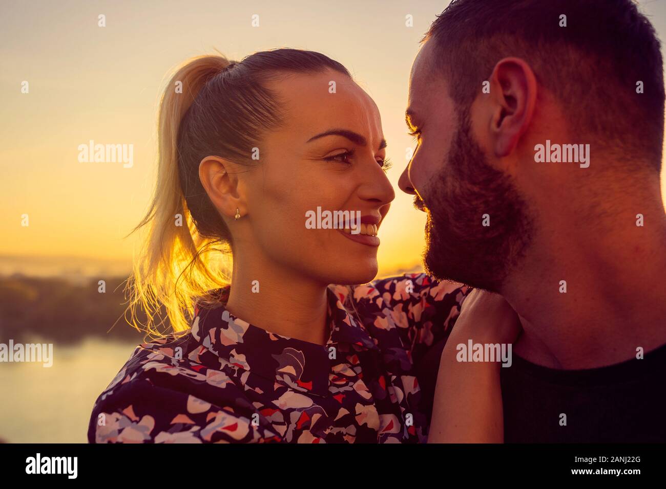 Couple romantique au coucher du soleil. Smiling young man and woman jouit de coucher du soleil Banque D'Images