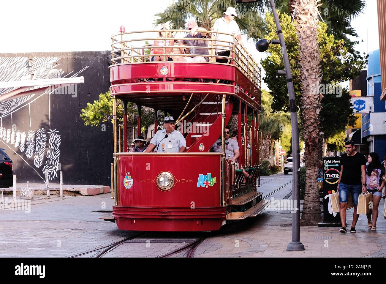 Un tramway ou un tramway peint aux couleurs vives fait son chemin le long d'une rue à Oranjestad sur l'île néerlandaise des Caraïbes d'Aruba. Ils sont exploités par Arubus Banque D'Images