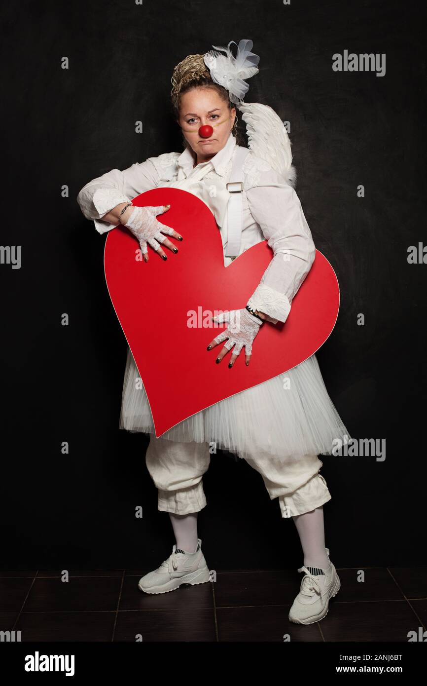 Clown femme posant avec un cœur rouge, studio portrait Banque D'Images