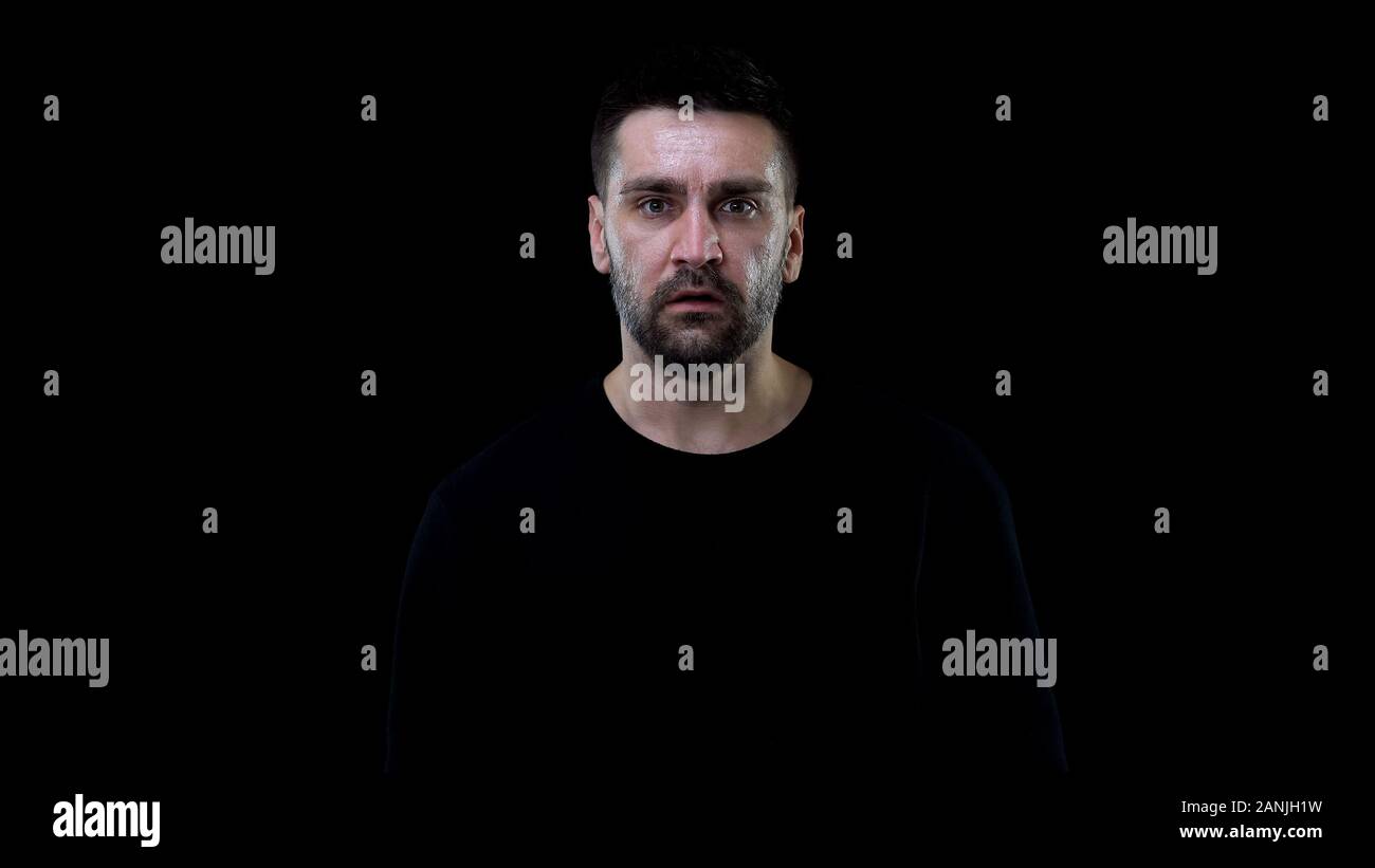 Homme effrayé à la caméra sur fond noir, nightmare horror, stress choc Banque D'Images