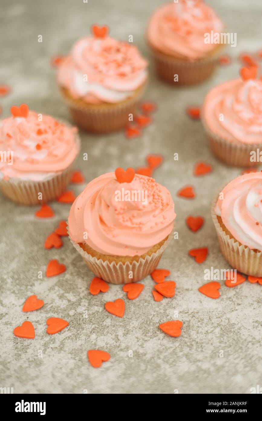 Cupcakes rose sur fond gris pour la Saint-Valentin. Bonbons cadeaux avec de la crème et saupoudrer avec le coeur. Banque D'Images