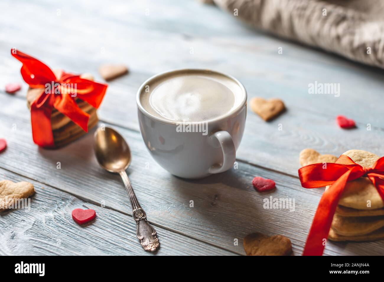 Tasse de café et un joli cadeau de cookies attachées avec du ruban rouge en forme de cœur sur un fond en bois bleu. Cadeaux de la saint Valentin romantique Banque D'Images