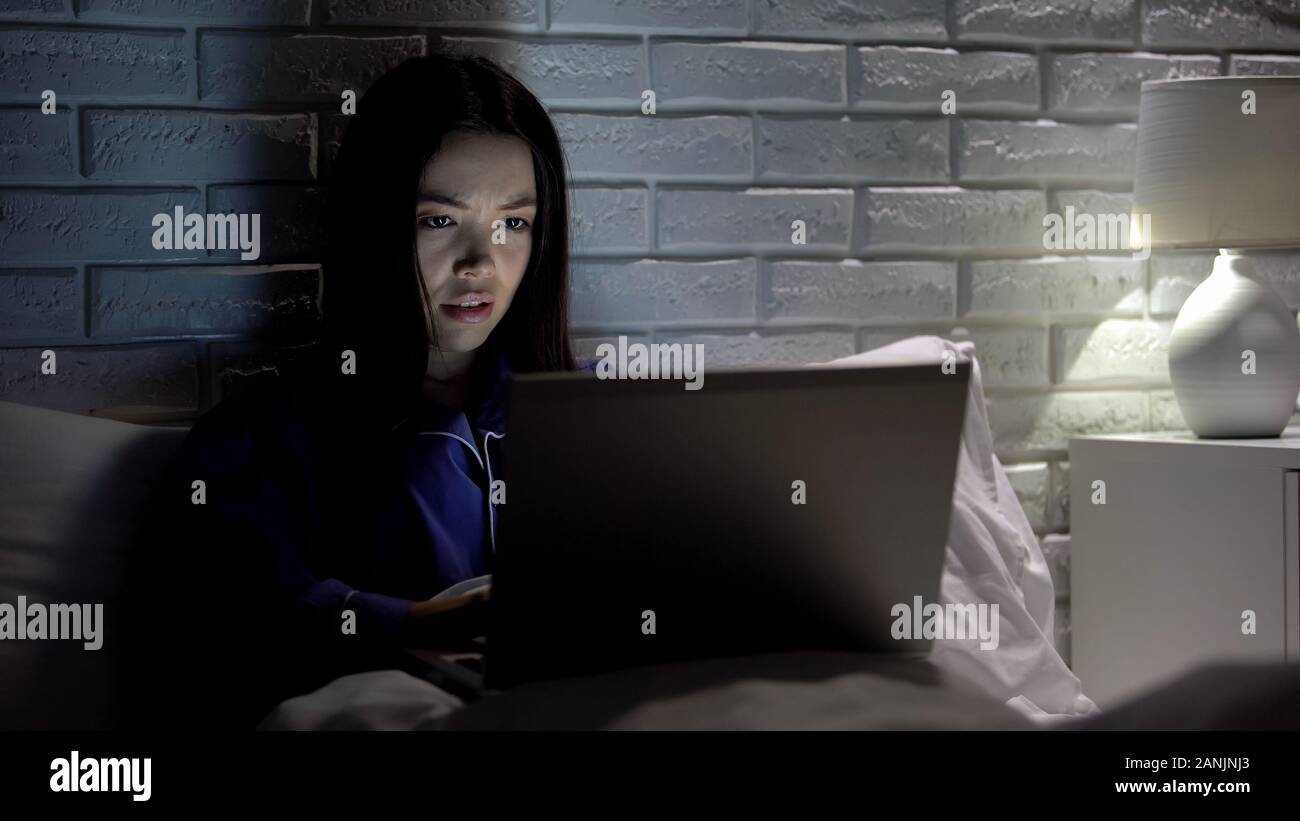 Girl working on laptop in l'heure du coucher, nerveux à l'écoute, le logiciel internet lent Banque D'Images