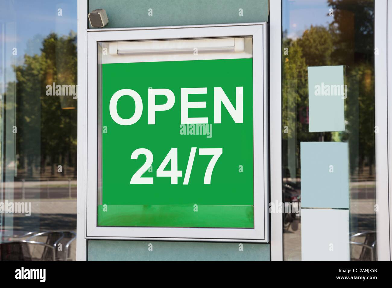 Close-up of Green ouvert 24h/24 Information Board accroché sur la porte de verre Banque D'Images
