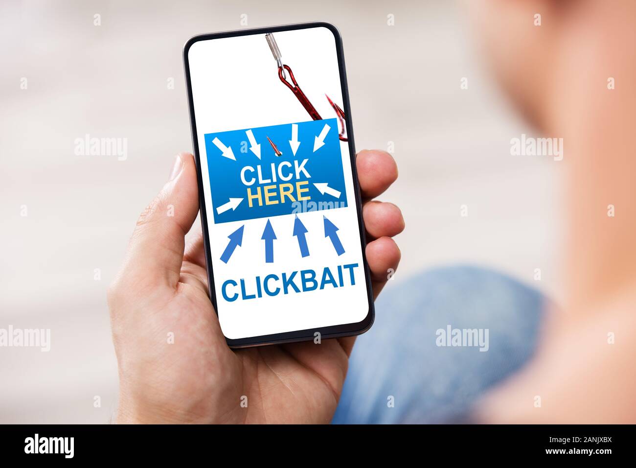 Person's Hand Holding Mobile Phone avec Clickbait Banque D'Images